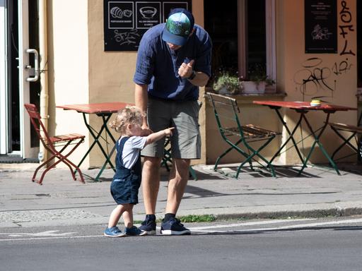 Ein Vater übt mit seinem Kind, wie man sicher die Straße überqueren kann.