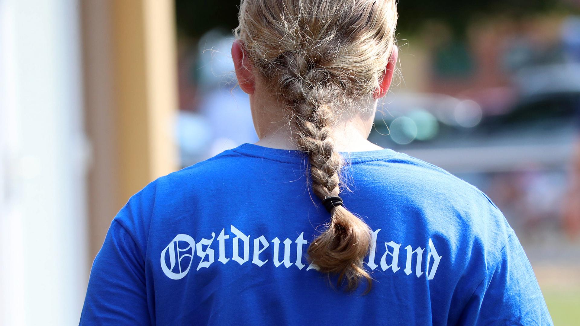 Ein blondes Mädchen mit Zopf trägt ein blaues Shirt mit der Aufschrift "Ostdeutschland", 2023.