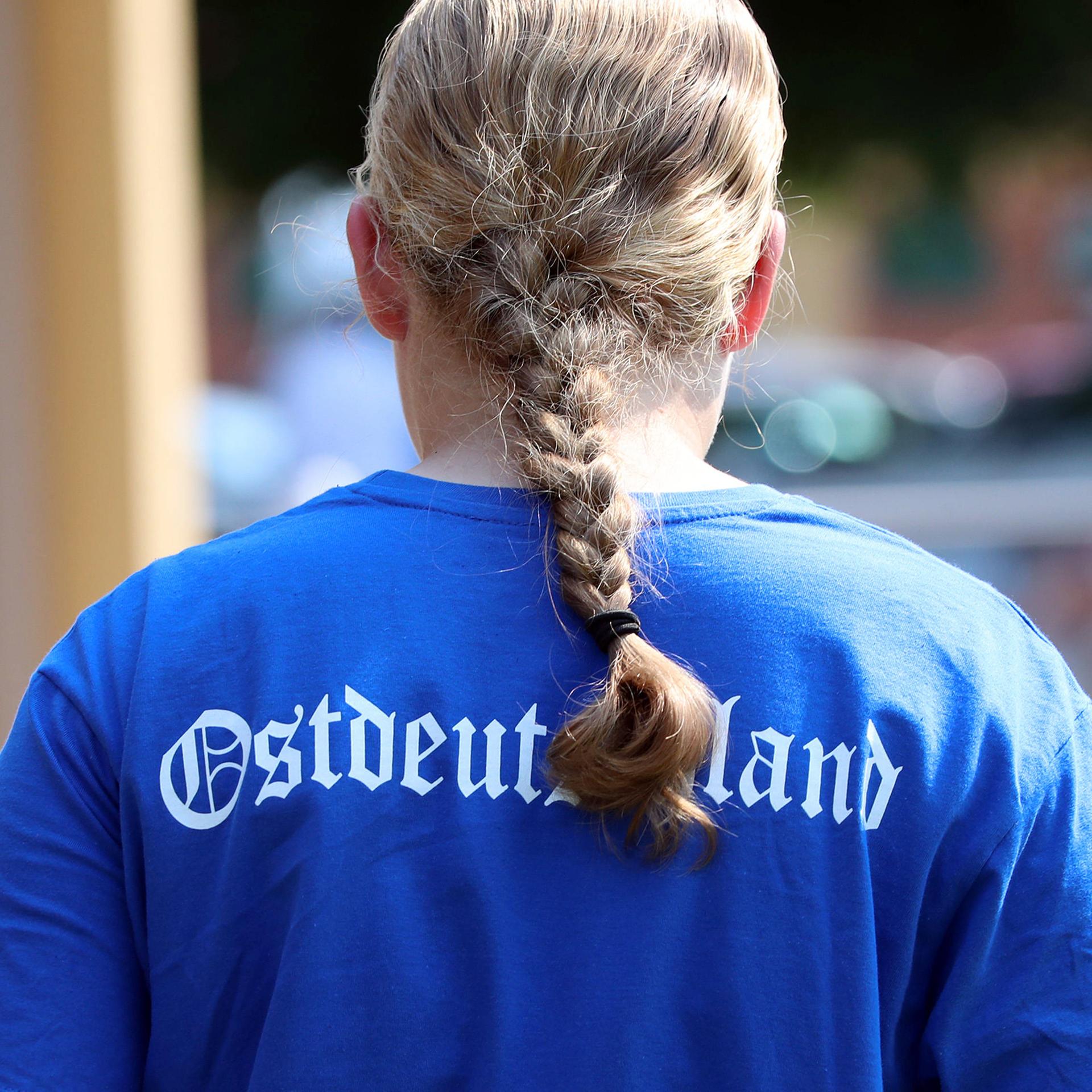Ein blondes Mädchen mit Zopf trägt ein blaues Shirt mit der Aufschrift "Ostdeutschland", 2023.