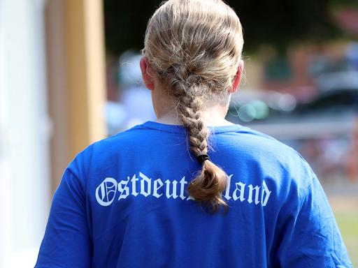 Ein blondes Mädchen mit Zopf trägt ein blaues Shirt mit der Aufschrift "Ostdeutschland", 2023.