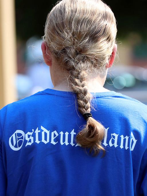 Ein blondes Mädchen mit Zopf trägt ein blaues Shirt mit der Aufschrift "Ostdeutschland", 2023.