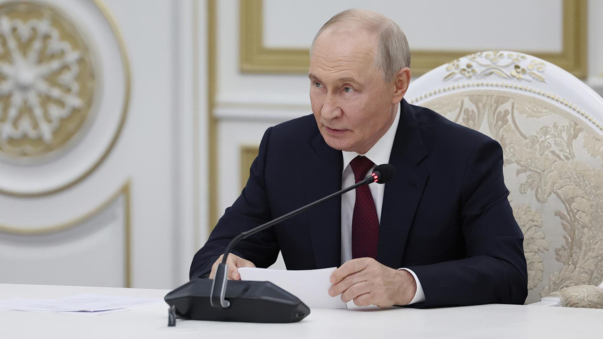 Der russische Präsident Wladimir Putin sitzt vor einem Mikrofon und gibt im Kreml eine Erklräung ab. 