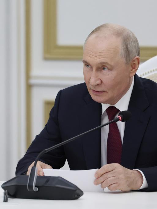 Der russische Präsident Wladimir Putin sitzt vor einem Mikrofon und gibt im Kreml eine Erklräung ab. 