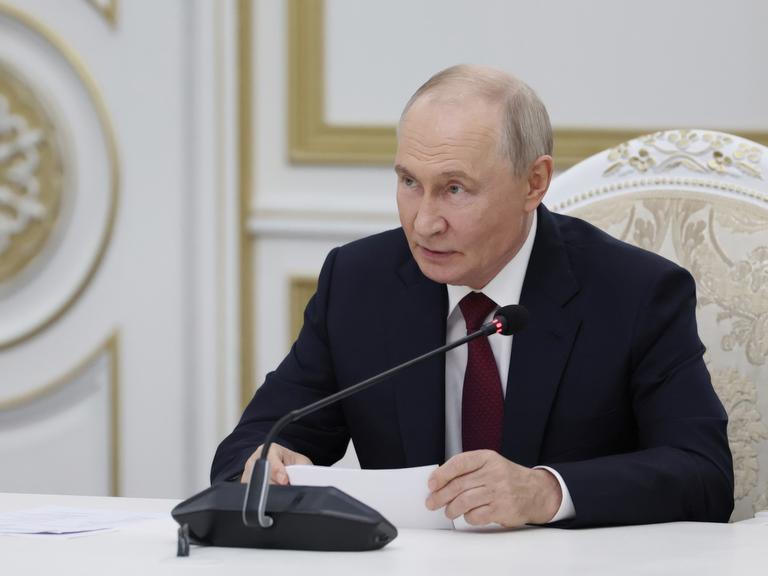 Der russische Präsident Wladimir Putin sitzt vor einem Mikrofon und gibt im Kreml eine Erklräung ab. 