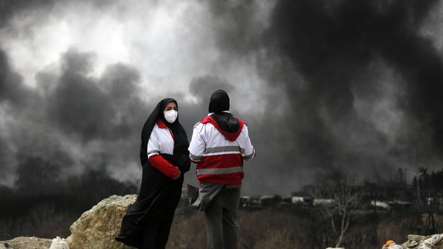 Zwei Personen stehen auf einer Annöhe und sehen schwarzer Rauch aufsteigen nach einem Angriff in Tehran.