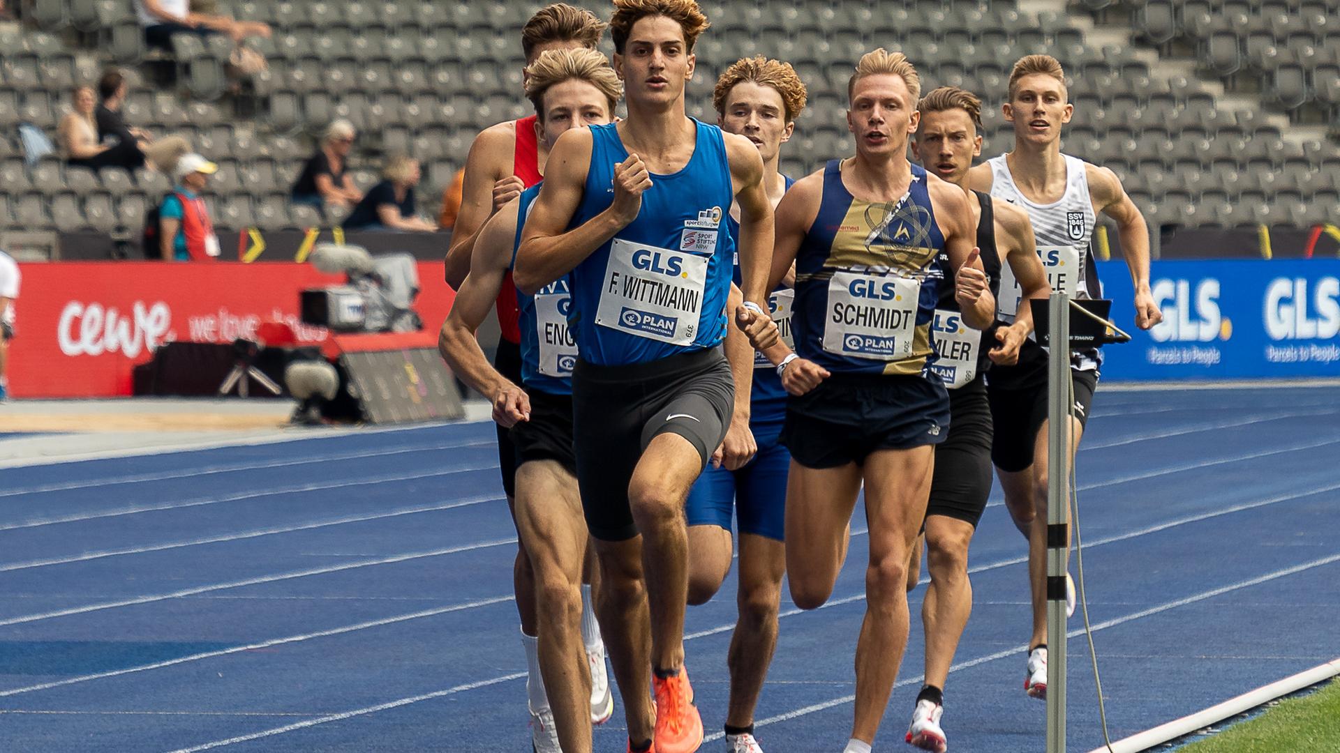 Felix Wittmann läuft als Erster von mehreren Sportlern auf einer blauen Tartanbahn im Stadion