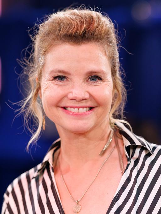 Schauspielerin Annette Frier trägt eine schwarzweiss gestreifte Bluse und lacht in die Kamera.