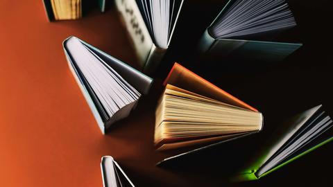 Durcheinander aufgestellte Bücher auf einem roten Tisch