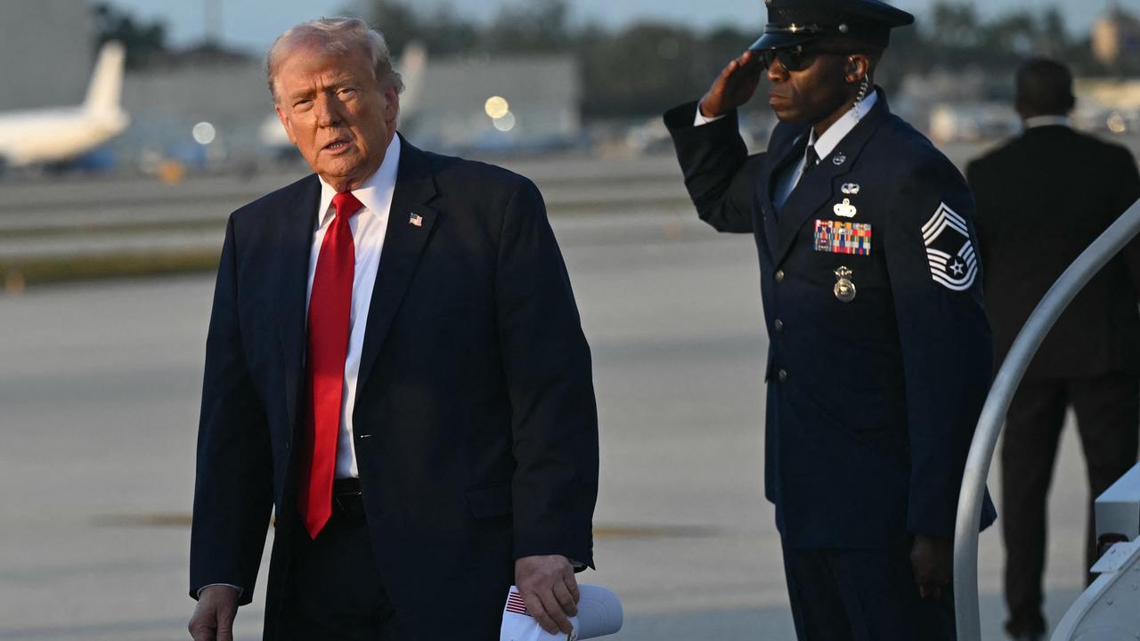 US-Präsident Trump verlässt sein Flugzeug, die Air Force One. Er blickt ernst in die Kamera, rechts von ihm salutiert ein Militärangehöriger. 