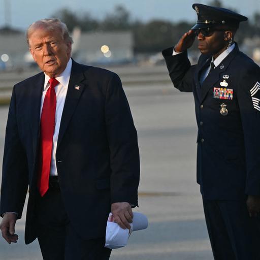 US-Präsident Trump verlässt sein Flugzeug, die Air Force One. Er blickt ernst in die Kamera, rechts von ihm salutiert ein Militärangehöriger. (Archivbild)