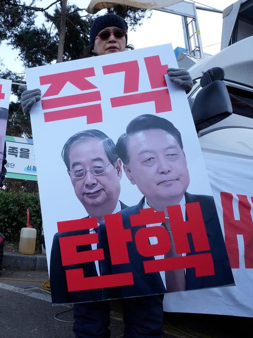 Demonstranten in Südkorea halten Plakate mit Bildern des abgesetzten Präsidenten Yoon Suk Yeol (rechts) und des ebenfalls mittlerweile abgesetzten Interimspräsidenten Han Duck-soo (links) in den Händen.