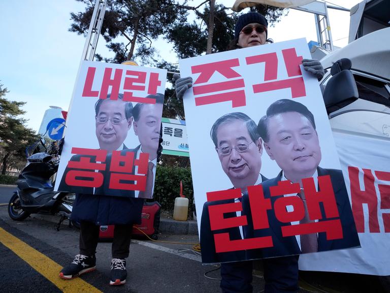 Demonstranten in Südkorea halten Plakate mit Bildern des abgesetzten Präsidenten Yoon Suk Yeol (rechts) und des ebenfalls mittlerweile abgesetzten Interimspräsidenten Han Duck-soo (links) in den Händen.