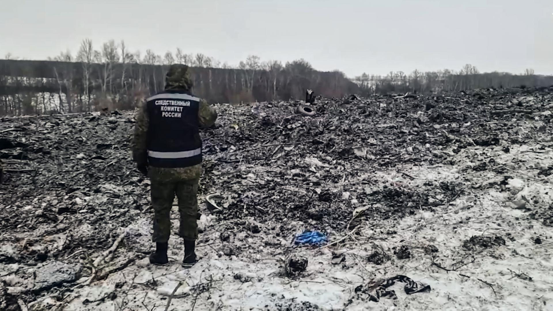 Ein russischer Ermittler steht vor einem Feld, auf dem sich Trümmer eines abgestürzten Flugzeugs befinden sollen.