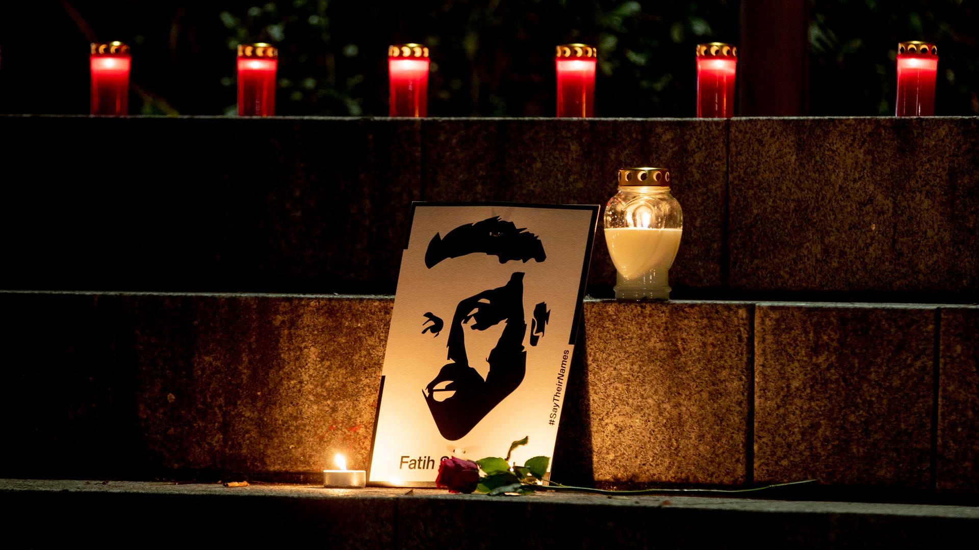 Auf einer Treppe steht eine Zeichnung eines Mannes, der bei dem rassistischen Anschlag in Hanau vor fünf Jahren ermordet wurde. Davor und auf den Stufen darüber brennen Kerzen. 
