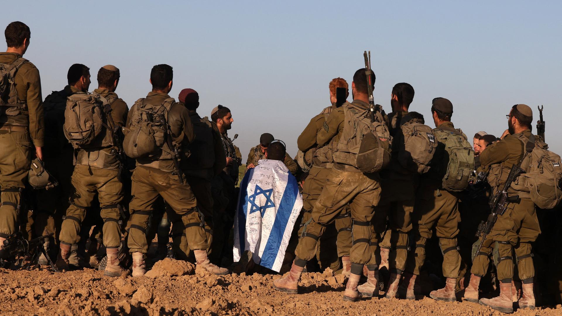 Israelische Soldaten stehen in einer Gruppe mit den Rücken zur Kamera. Einer hat sich eine israelische Flagge umgebunden. Israelische Soldaten stehen in einer Gruppe mit den Rücken zur Kamera. Einer hat sich eine israelische Flagge umgebunden.