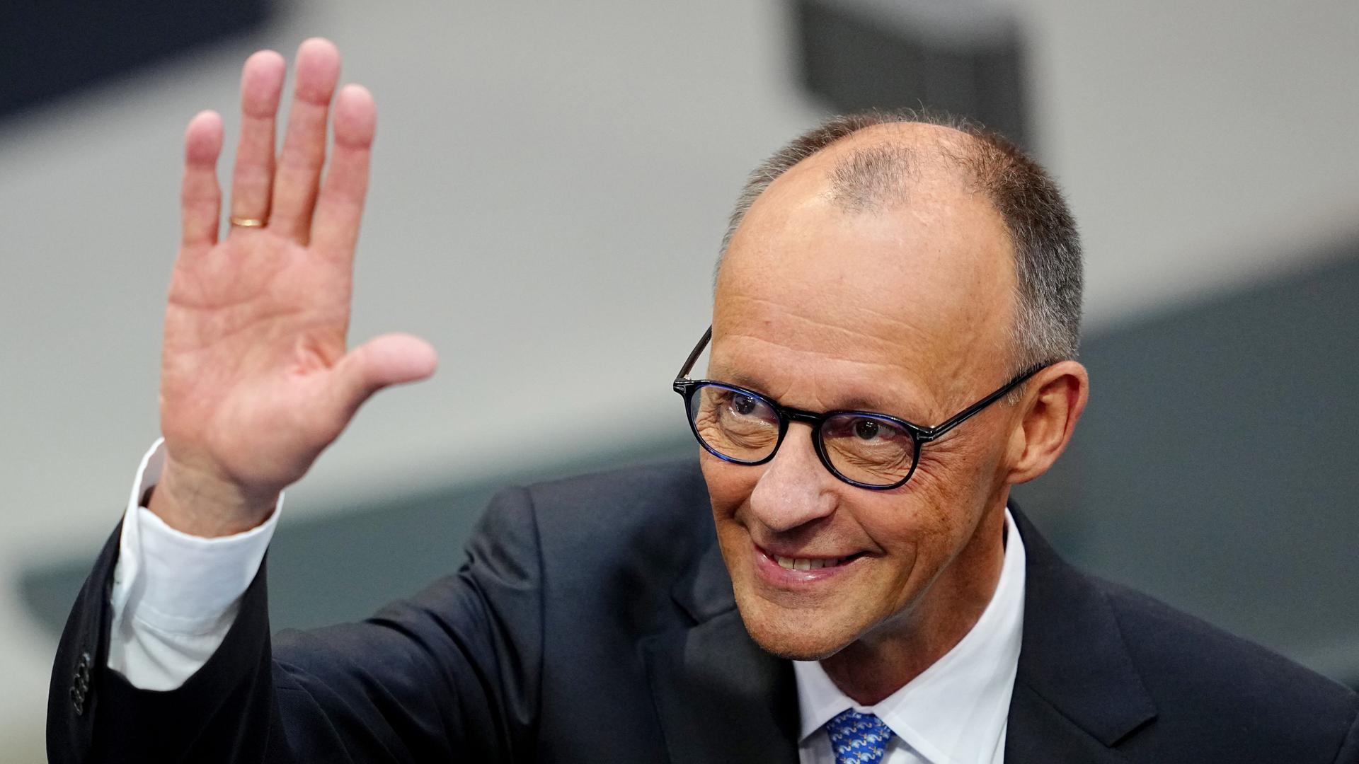 Der CDU-Vorsitzende Friedrich Merz winkt einer Person zu und lächelt. Der CDU-Vorsitzende Friedrich Merz winkt einer Person zu und lächelt.