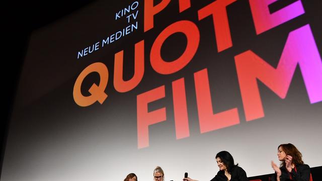 Mehrere Frauen sitzen nebeneinander vor einer Leinwand in einem Kinosaal. Auf der Leinwand steht "Quote Film".