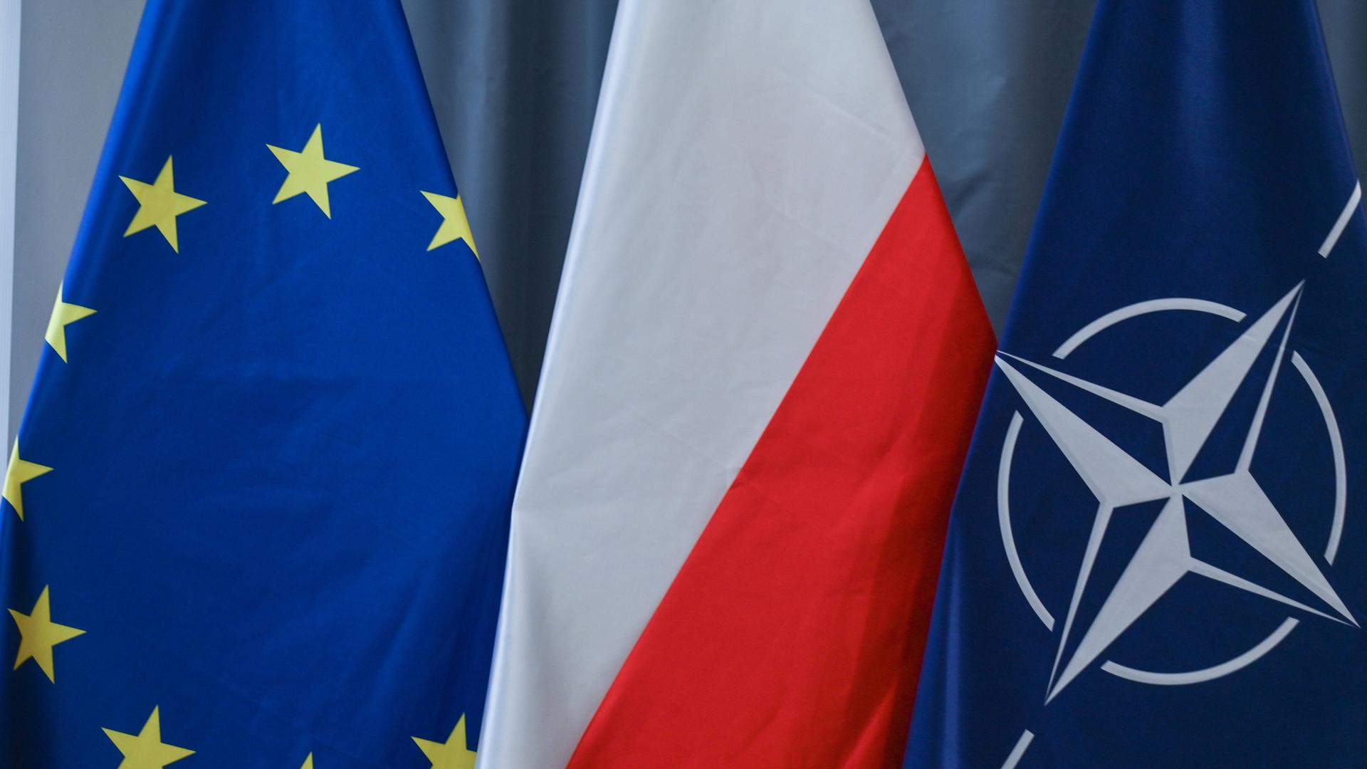 Drei Flaggen nebeneinander; die Flagge der EU, Polens und der NATO.