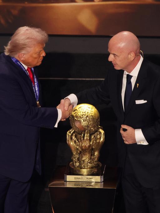 US-Präsident Donald Trump und FIFA-Präsident Gianni Infantino schütteln sich die Hände vor dem goldenen Pokal des FIFA-Friedenspreises für Trump.