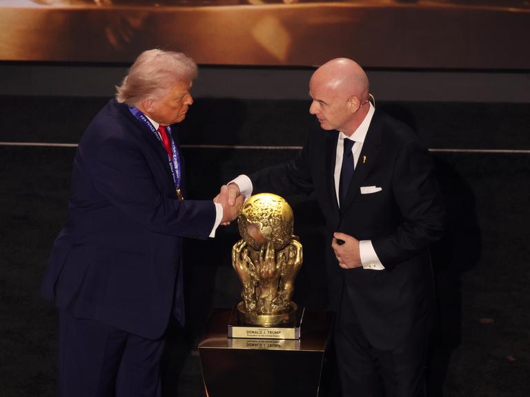 US-Präsident Donald Trump und FIFA-Präsident Gianni Infantino schütteln sich die Hände vor dem goldenen Pokal des FIFA-Friedenspreises für Trump.