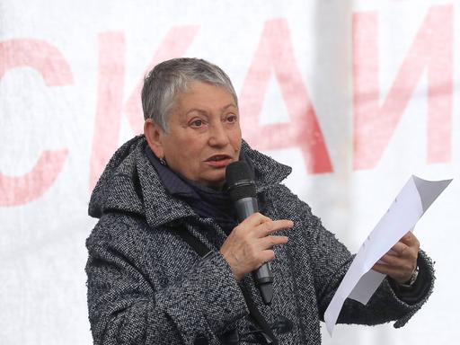 Ljudmila Ulitzkaja liest auf einer Bühne einen Text von einem Blatt Papier ab.