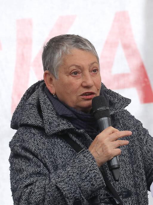 Ljudmila Ulitzkaja liest auf einer Bühne einen Text von einem Blatt Papier ab.