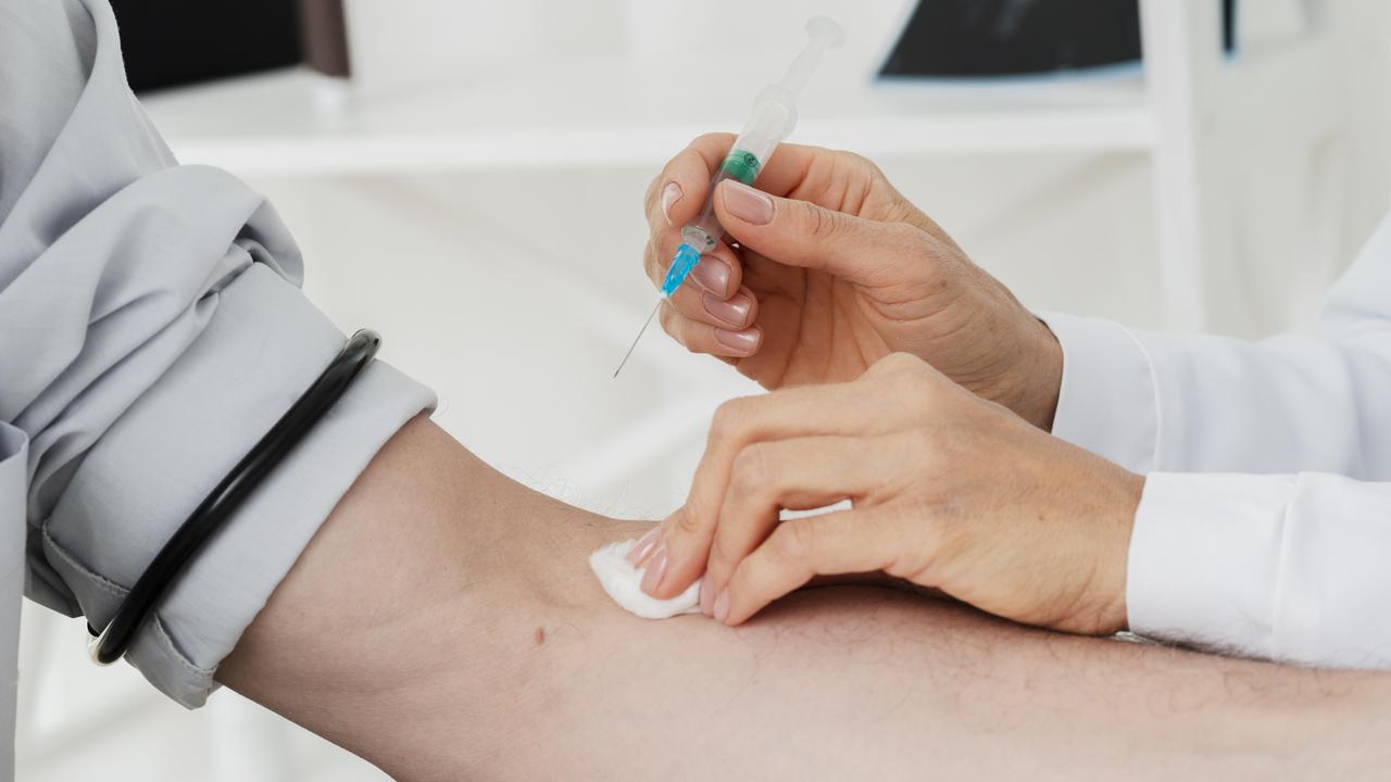 Gezeigt ist, wie eine intravenöse Injektion verabreicht wird. Der Ärmel eines Patienten ist hochgekrempelt. Eine medizinische Fachkraft desinfiziert die Stelle in der Armbeuge, wo eine Kanüle angesetzt werden soll. 