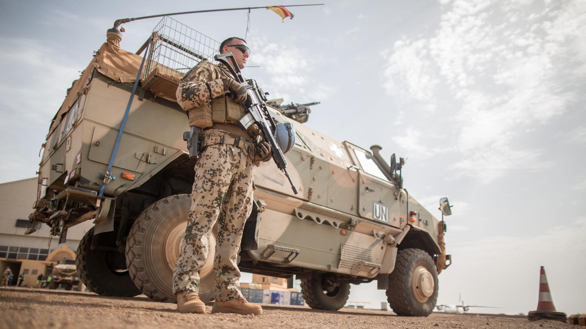 Ein Bundeswehrsoldat steht am Flughafen nahe des Camp Castor in Gao in Mali vor einem Militärfahrzeug