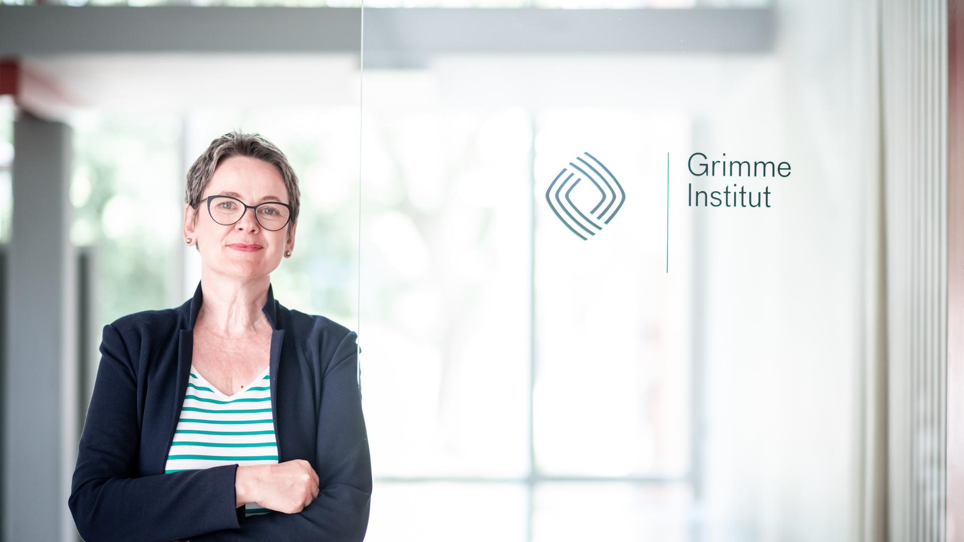 Grimme-Instituts-Chefin Frauke Gerlach neben einer Glastür mit Grimme-Aufschrift