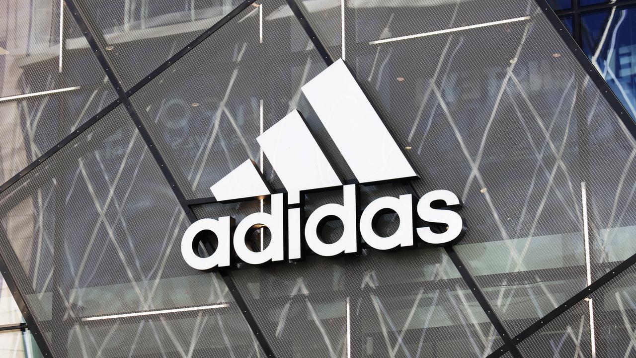 Zu sehen ist das Adidas-Logo an der Glasfassade eines Gebäudes.