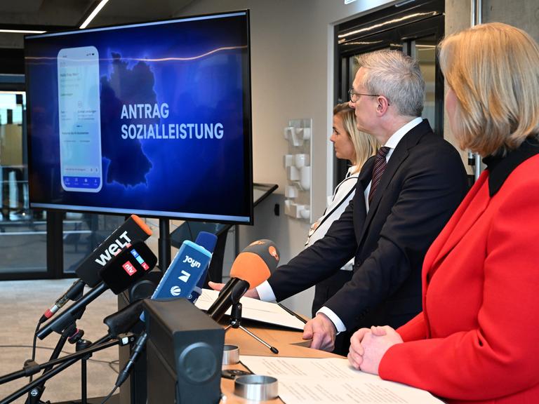 Bärbel Bas (r, SPD), Bundesministerin für Arbeit und Soziales, und Karsten Wildberger (CDU), Bundesminister für Digitalisierung und Staatsmodernisierung (BMDS), verfolgen gemeinsam mit BMDS-Sprecherin Betty Kieß (l) eine Videopräsentation.
