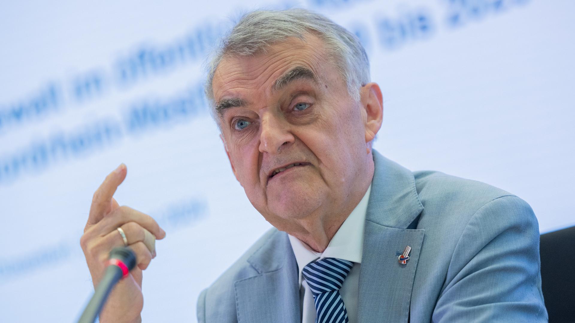 Herbert Reul spricht auf einer Pressekonferenz mit ernster Mine in ein Mikrofon.