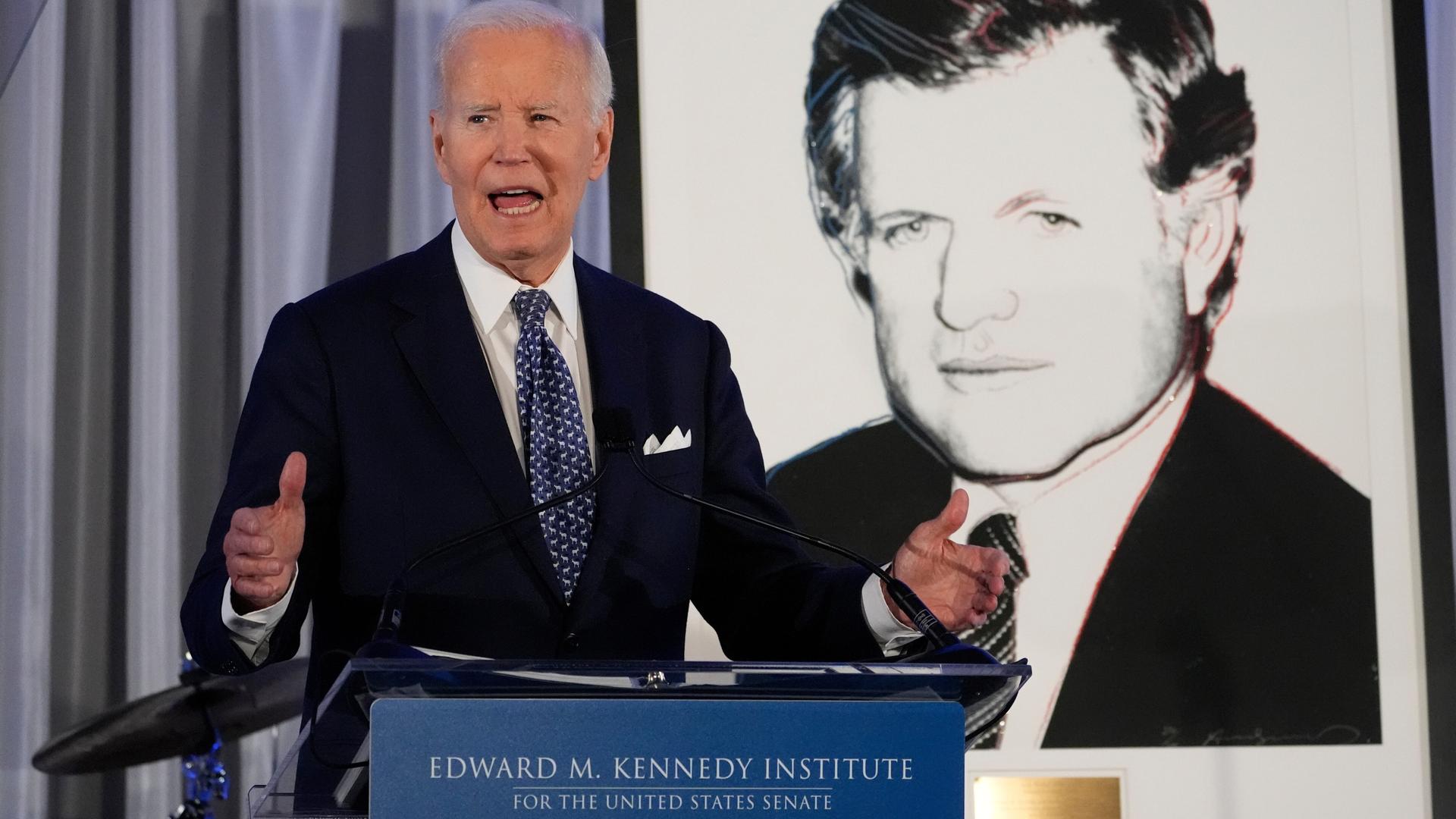 Biden spricht am Edward M. Kennedy Institute, wo er eine Auszeichnung für sein Lebenswerk bekam. Hinter ihm das Porträt von Kennedy.