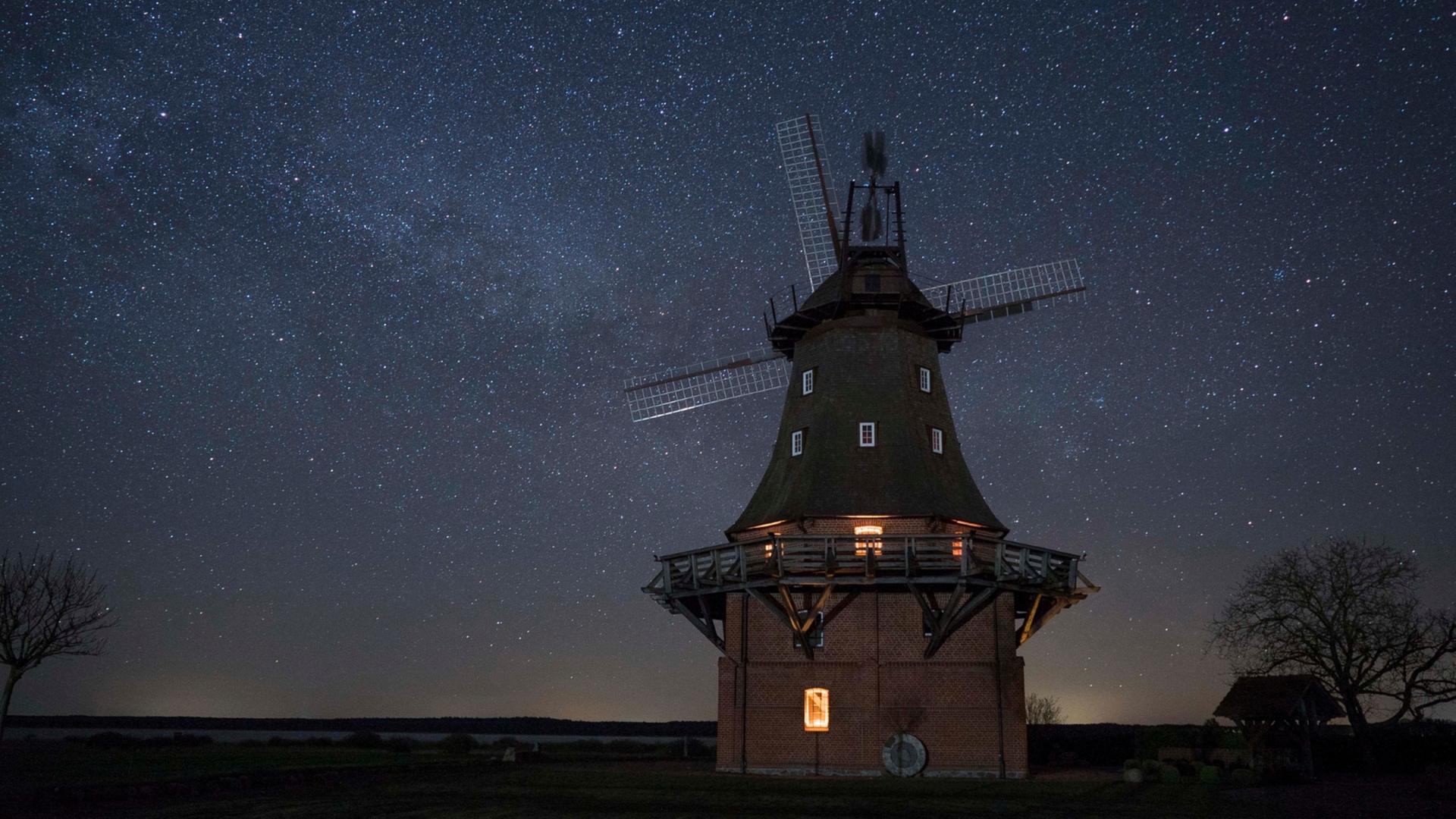 Eine Mühle steht vor nächtlichem Sternenhimmel.