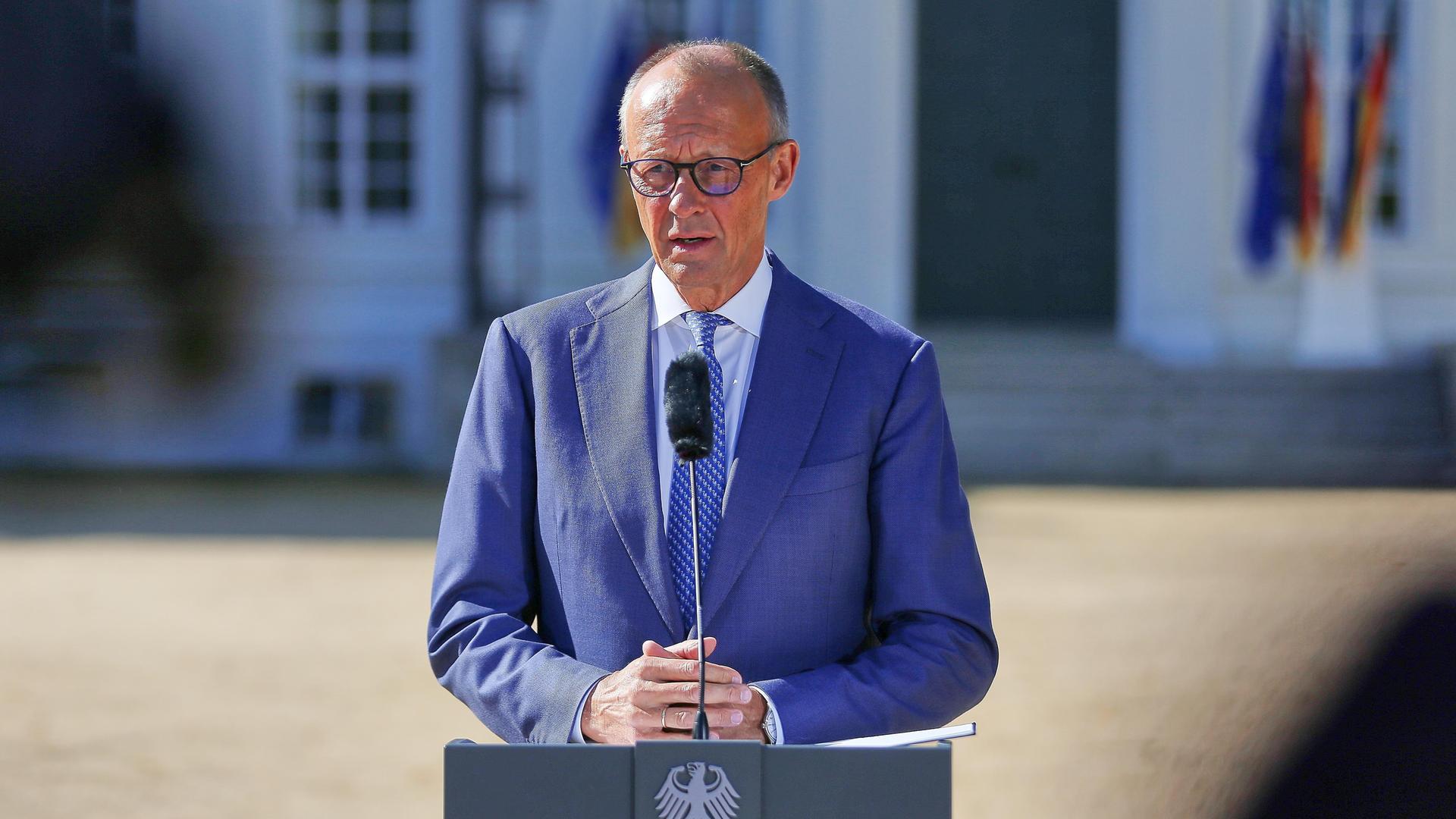 Bundeskanzler Friedrich Merz (CDU) spricht am Rednerpult bei seiner Ankunft im Schloss Neuhardenberg.
