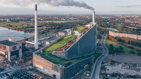 Vogelperspektive auf ein großes Kraftwerk mit einer Skipiste auf dem Dach.