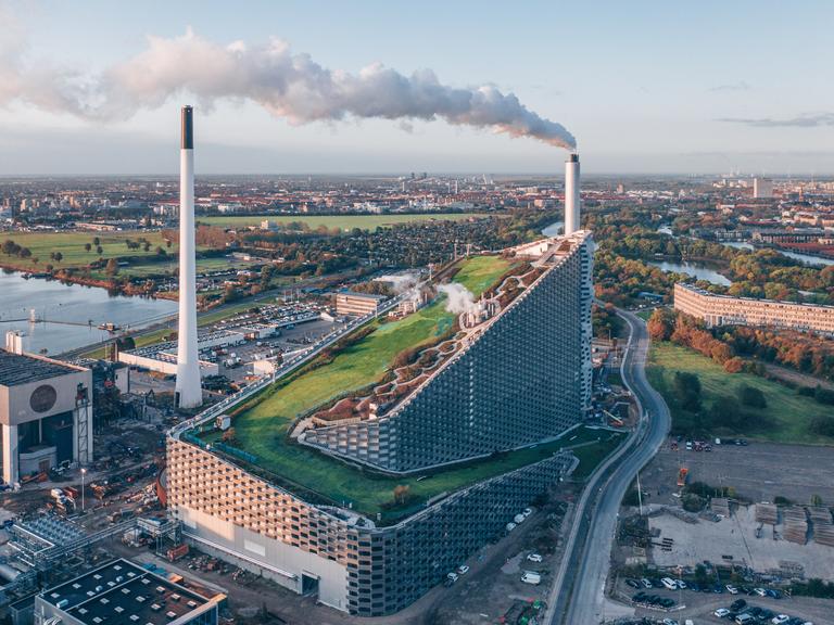 Vogelperspektive auf ein großes Kraftwerk mit einer Skipiste auf dem Dach.