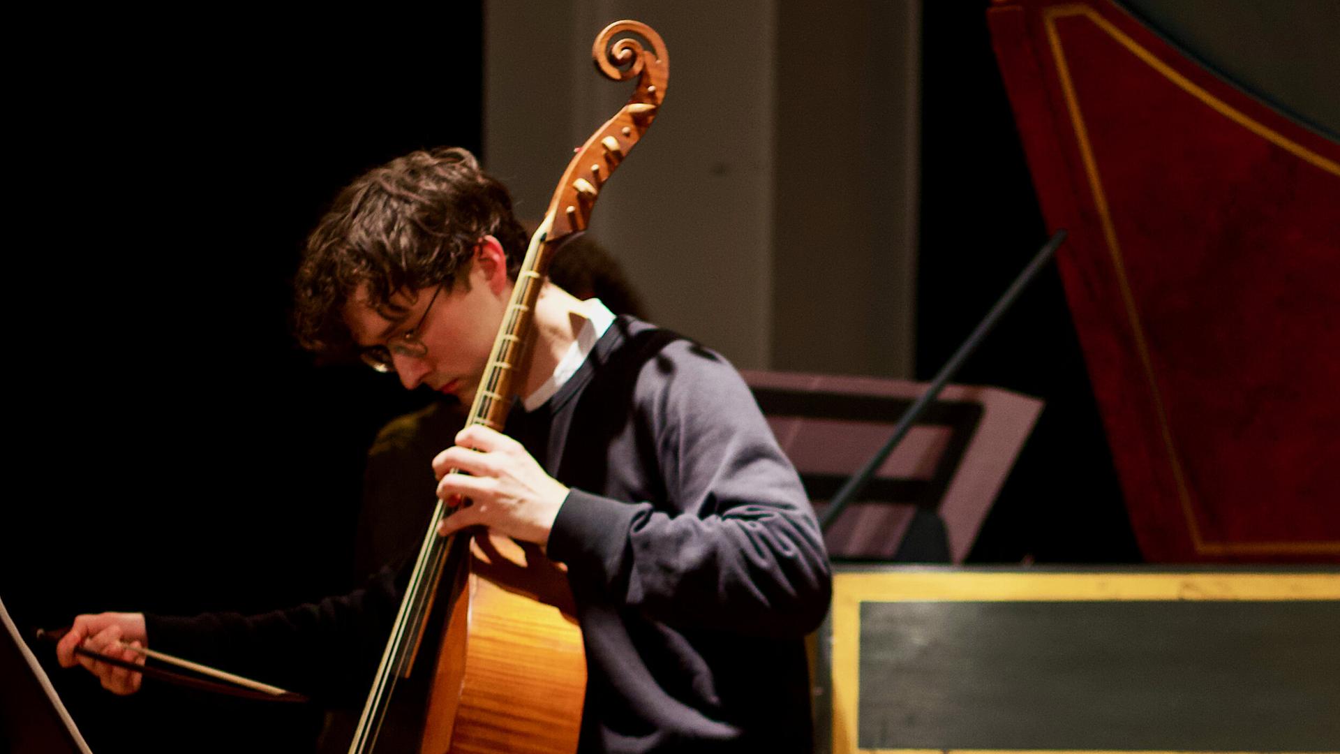 Ein Mann an der Viola da gamba den Blick auf sein Instrument gerichtet. 