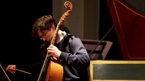 Ein Mann an der Viola da gamba den Blick auf sein Instrument gerichtet. 