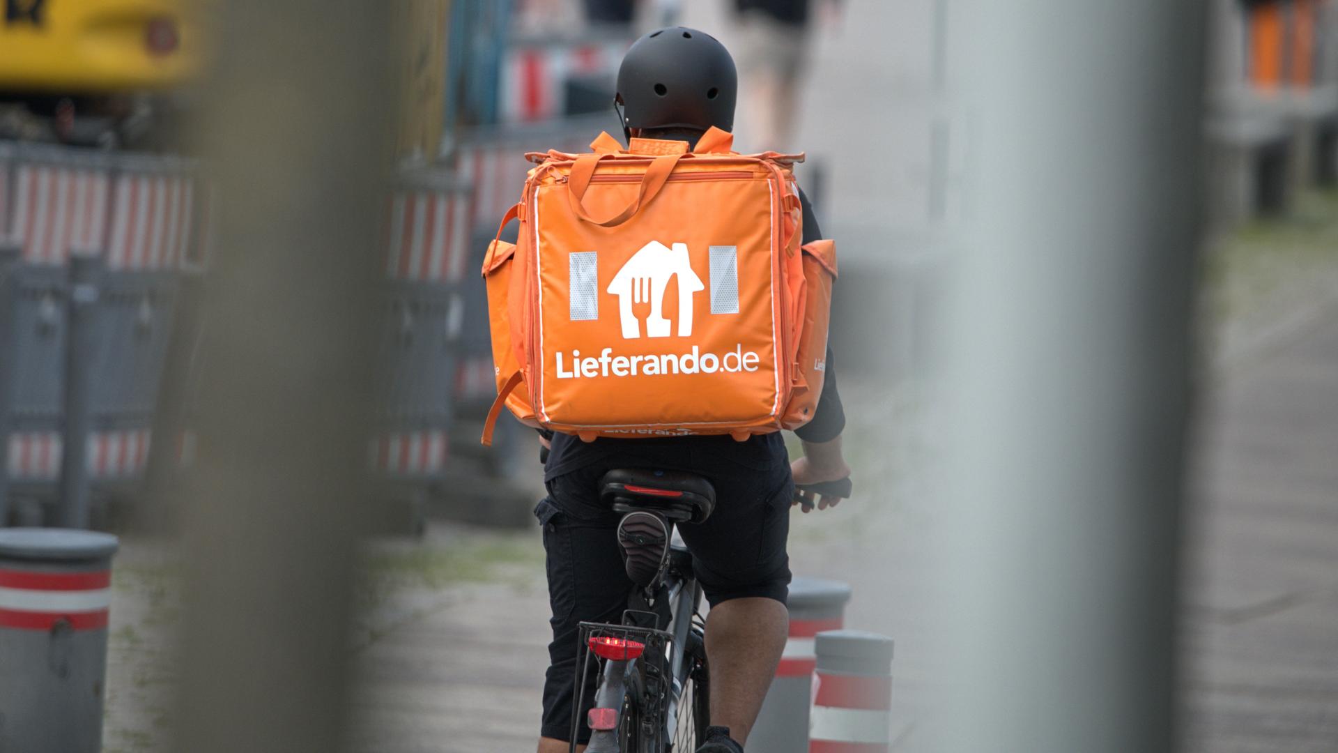 Ein Fahrradkurier des Fastfood-Lieferdienstes Lieferando.de mit Helm im Einsatz.