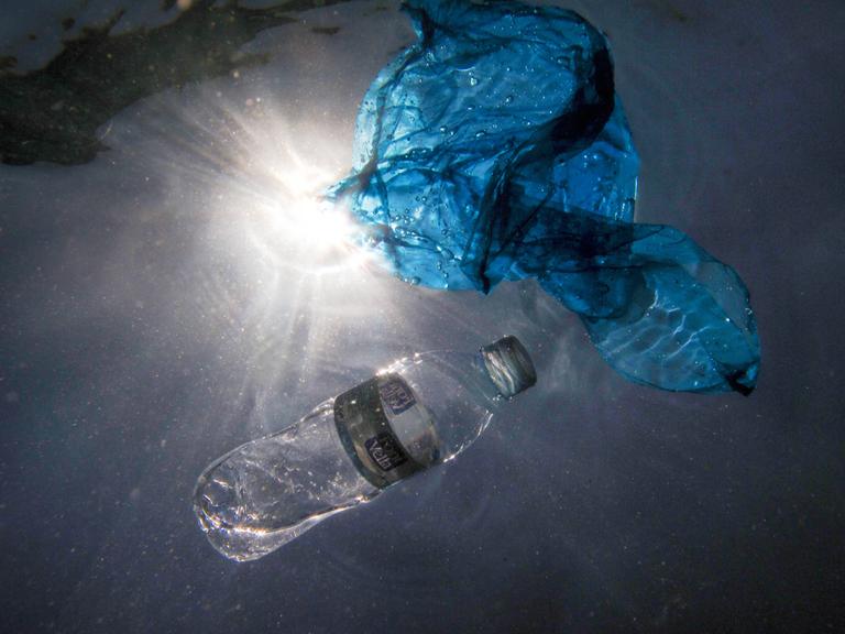 Unterwasseraufnahme von Plastik-Abfall in Form einer PET Flasche und einer Plastiktüte.
