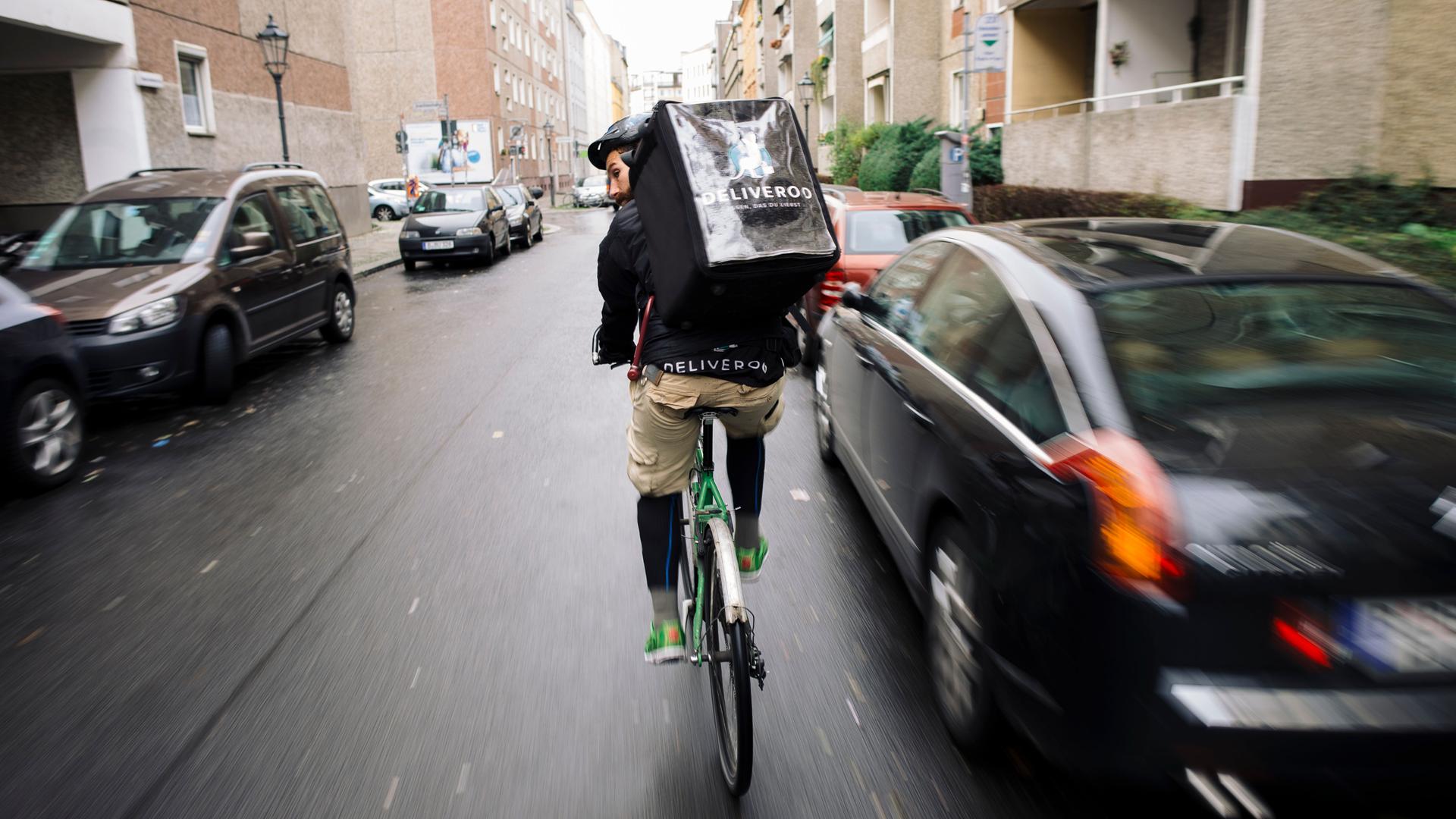 Ein Fahrradkurier fährt mit seinem Fahrrad durch den Stadtverkehr in Berlin.