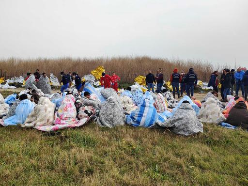 Gerettete Flüchtlinge sitzen in Decken gehüllt an einem Strand in der Nähe von Cutro in Süditalien.