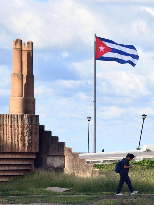 Ein Mann geht an einer Kubanischen Nationalflagge in Havanna vorbei.
