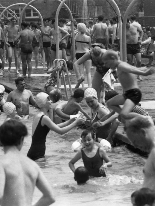 Schwarz-weiß Foto: Viele Menschen im Freibad, das Becken ist voll.
