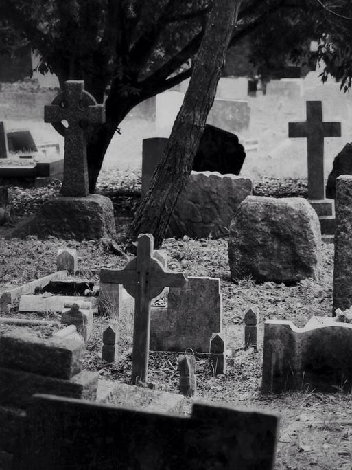 Schwarz-Weiß-Bild von Grabsteinen auf einem Friedhof