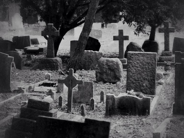 Schwarz-Weiß-Bild von Grabsteinen auf einem Friedhof