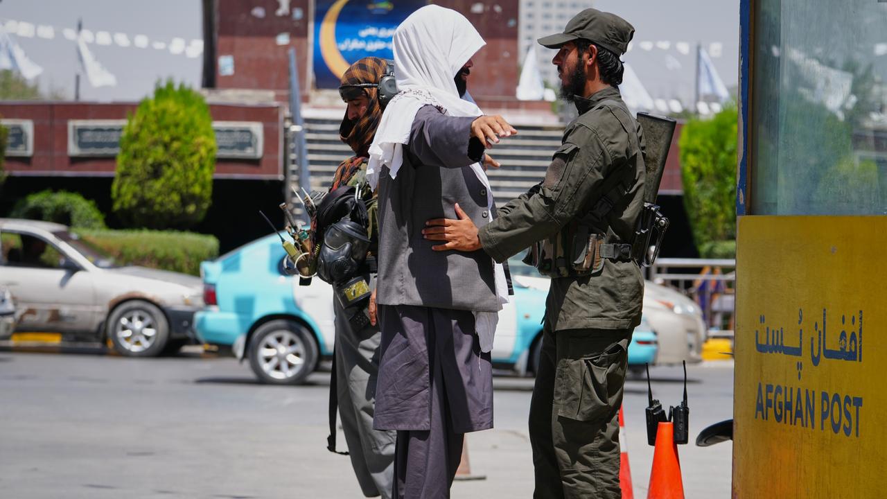 Ein uniformierter und bewaffneter Sicherheitsoffizier der islamistischen Taliban kontrolliert an einem Checkpoint auf der Straße in Kabul einen Mann. Ein uniformierter und bewaffneter Sicherheitsoffizier der islamistischen Taliban kontrolliert an einem Checkpoint auf der Straße in Kabul einen Mann.