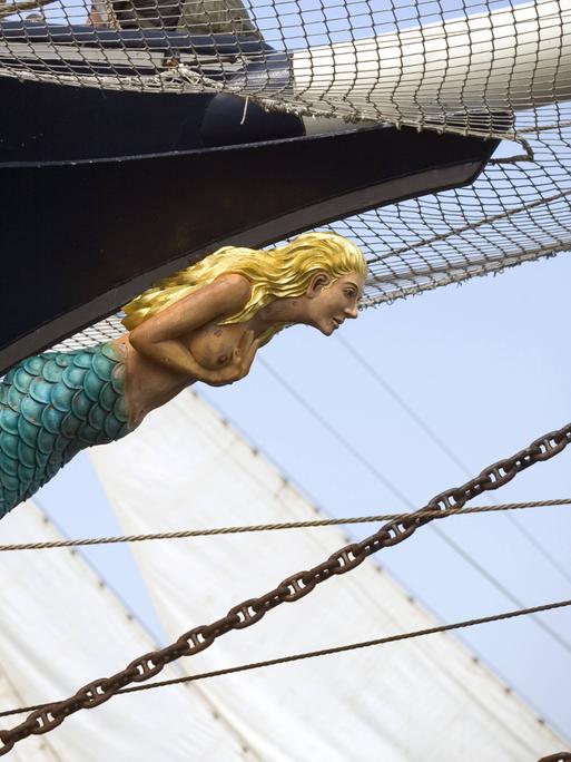 Blick auf eine blonde Meerjungfrau aus Holz, die als Galisonsfigur ein Segelschiff ziert.