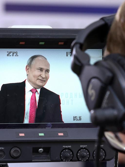 Der russische Präsident Wladimir Putin ist auf dem Bildschirm einer Fernsehkamera zu sehen, während er auf einem Forum. 
